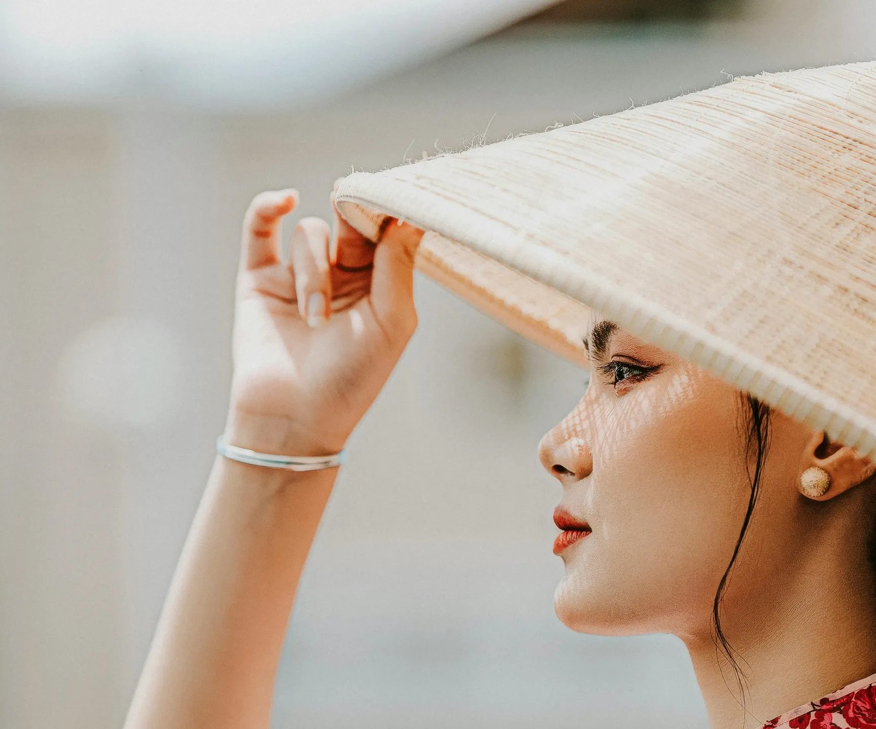 The image of a beautiful Vietnamese lady holding her cone-shaped hat and looking ahead, symbolizing the dreamy adventure of traveling to Vietnam