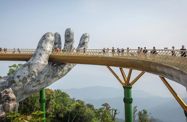 Tourists walking on Golden Bridge held by giant hands at Ba Na Hills in Da Nang, Vietnam