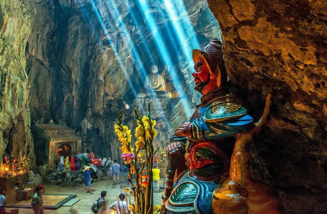 Adventurer exploring illuminated Am Phu Cave in Marble Mountains during sunset tour in Da Nang