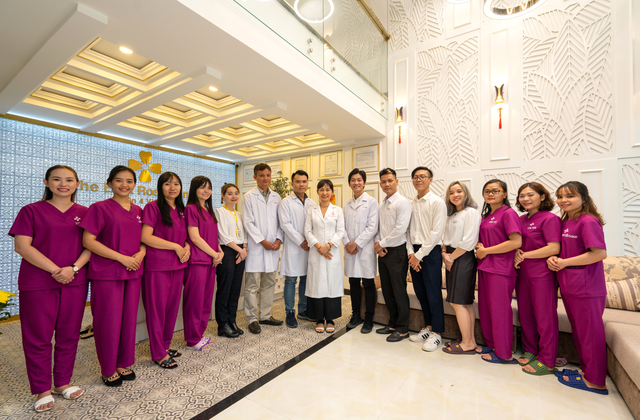 East Rose Dental Clinic Vietnam team of dentists, hygienists, and administrative staff standing together in modern clinic reception area