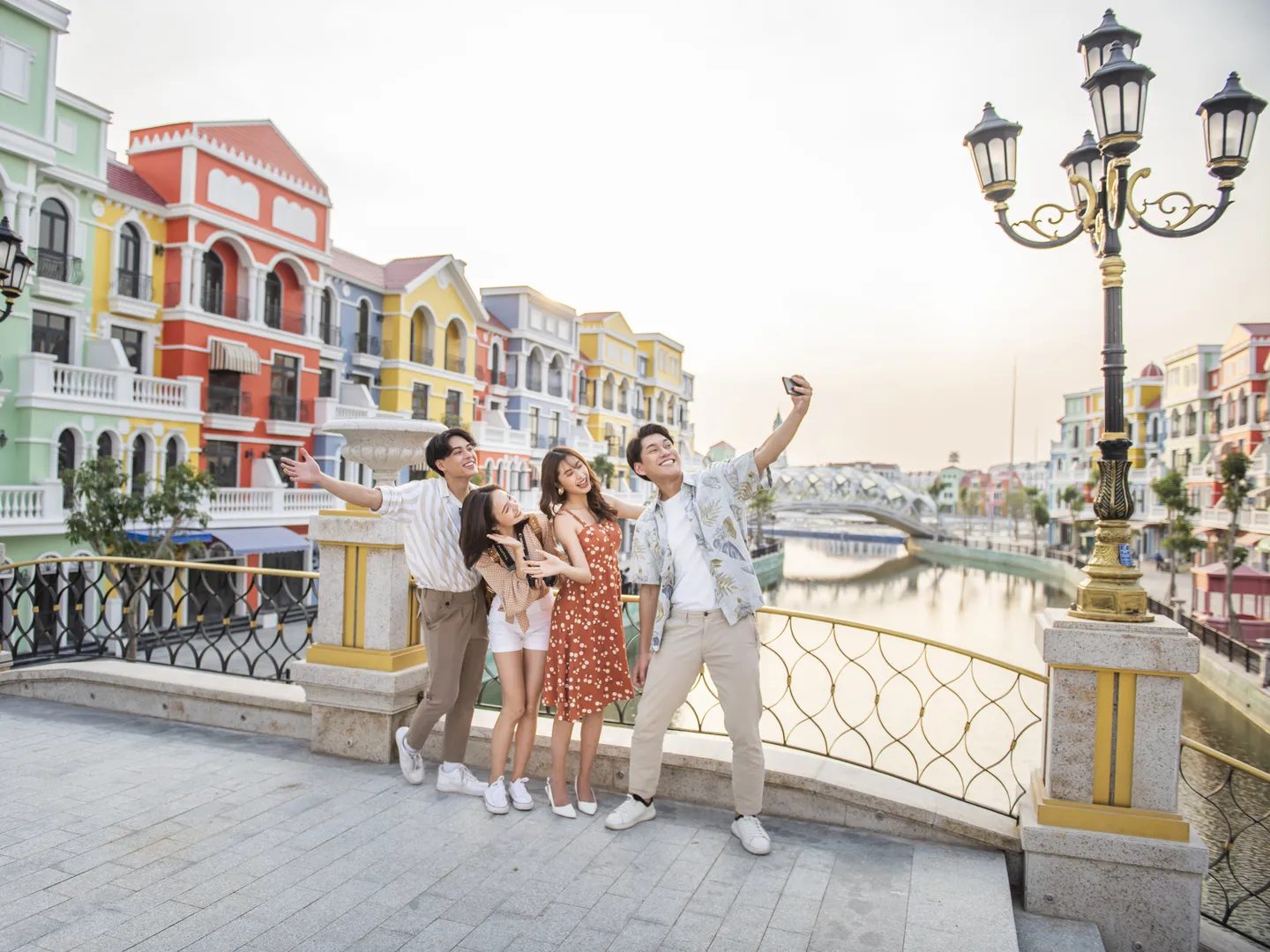  A group of friends taking selfie moments on the bridge with street lights reminiscing of an atmosphere of a European village in Grand World Phu Quoc- a popular tourism destination in Vietnam 